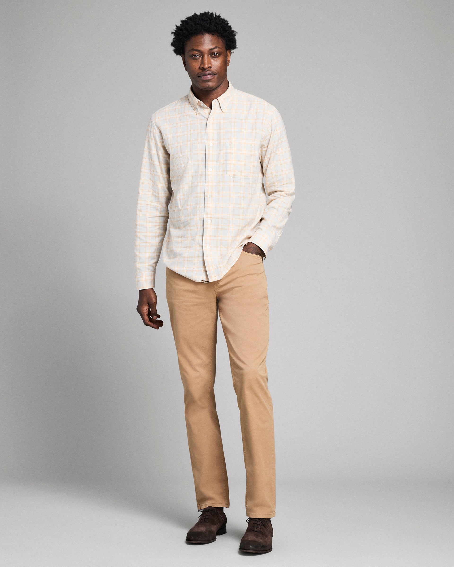 Man wearing a light-colored shirt and beige pants against a gray background