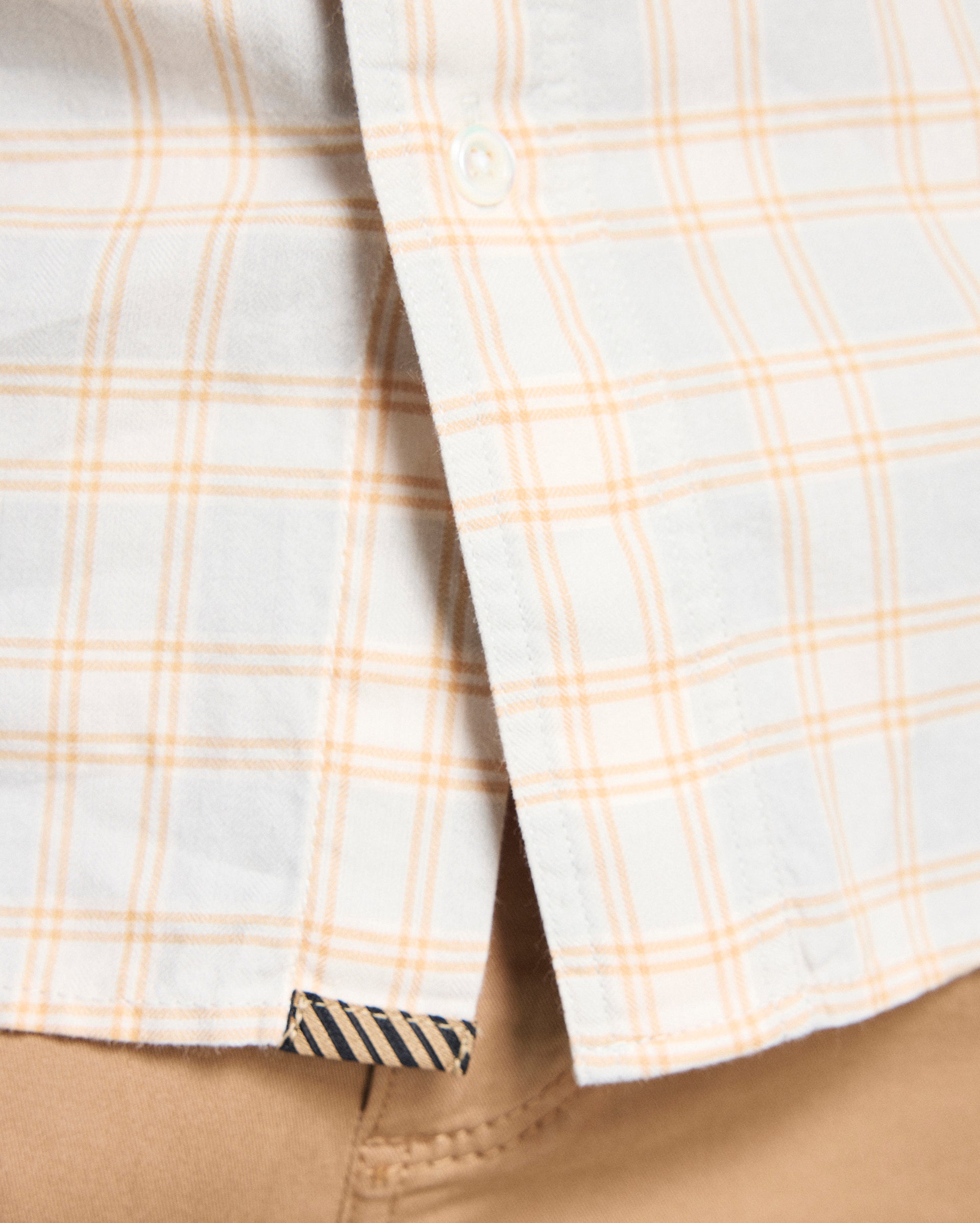 Close-up of a plaid shirt with beige and white pattern on a beige background