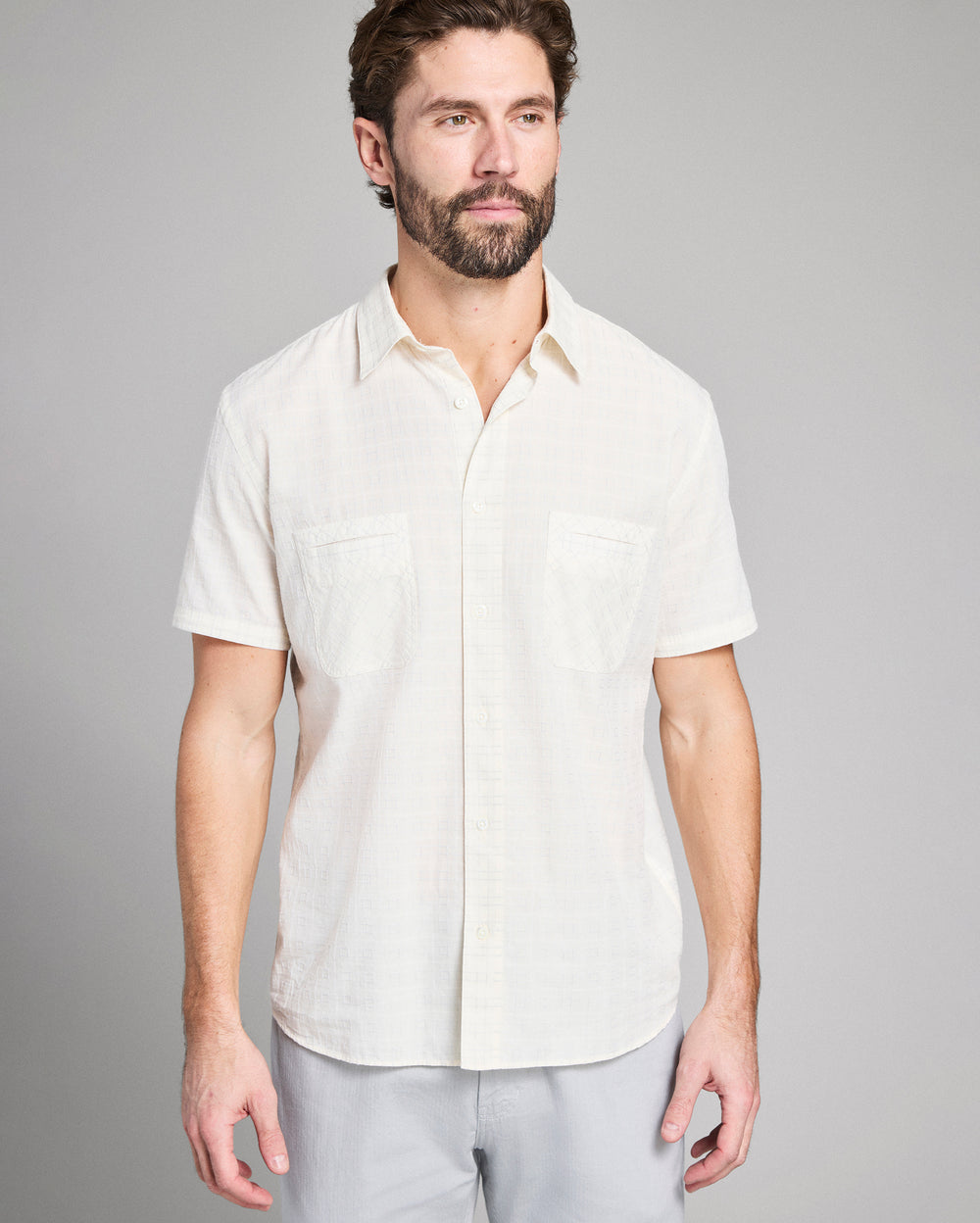 Man wearing a white short-sleeve shirt against a gray background