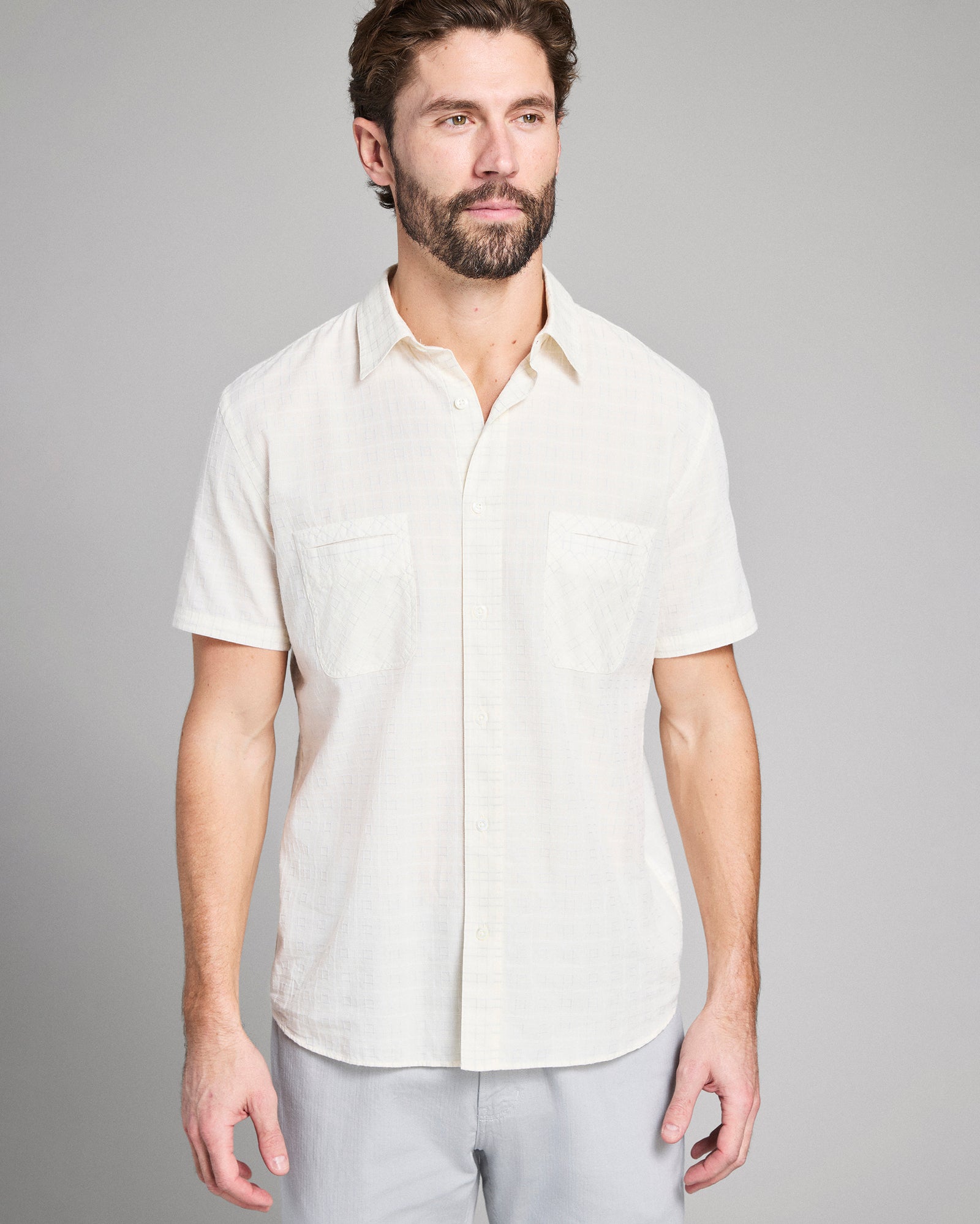 Man wearing a white short-sleeve shirt against a gray background