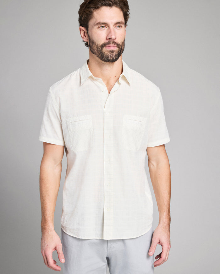 Man wearing a white short-sleeve shirt against a gray background