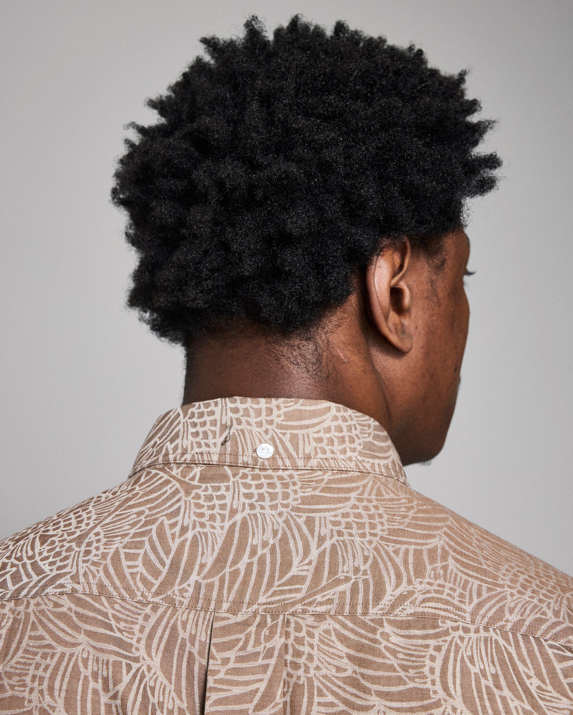 Person wearing a patterned shirt against a plain background