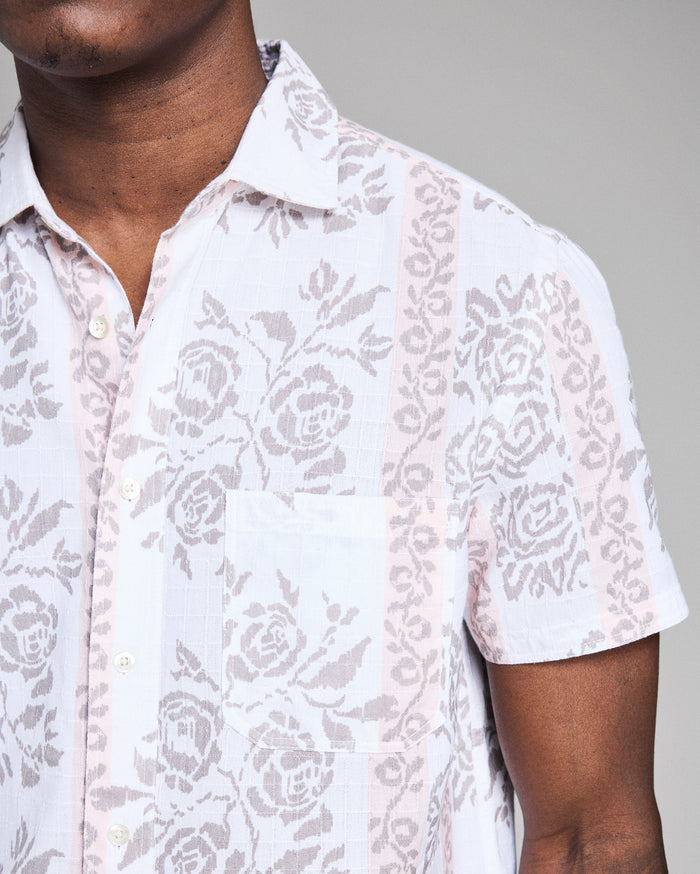 White floral patterned shirt worn by a person on a gray background