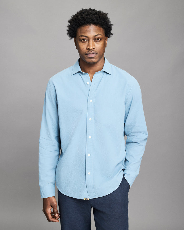 Man wearing a light blue shirt against a gray background