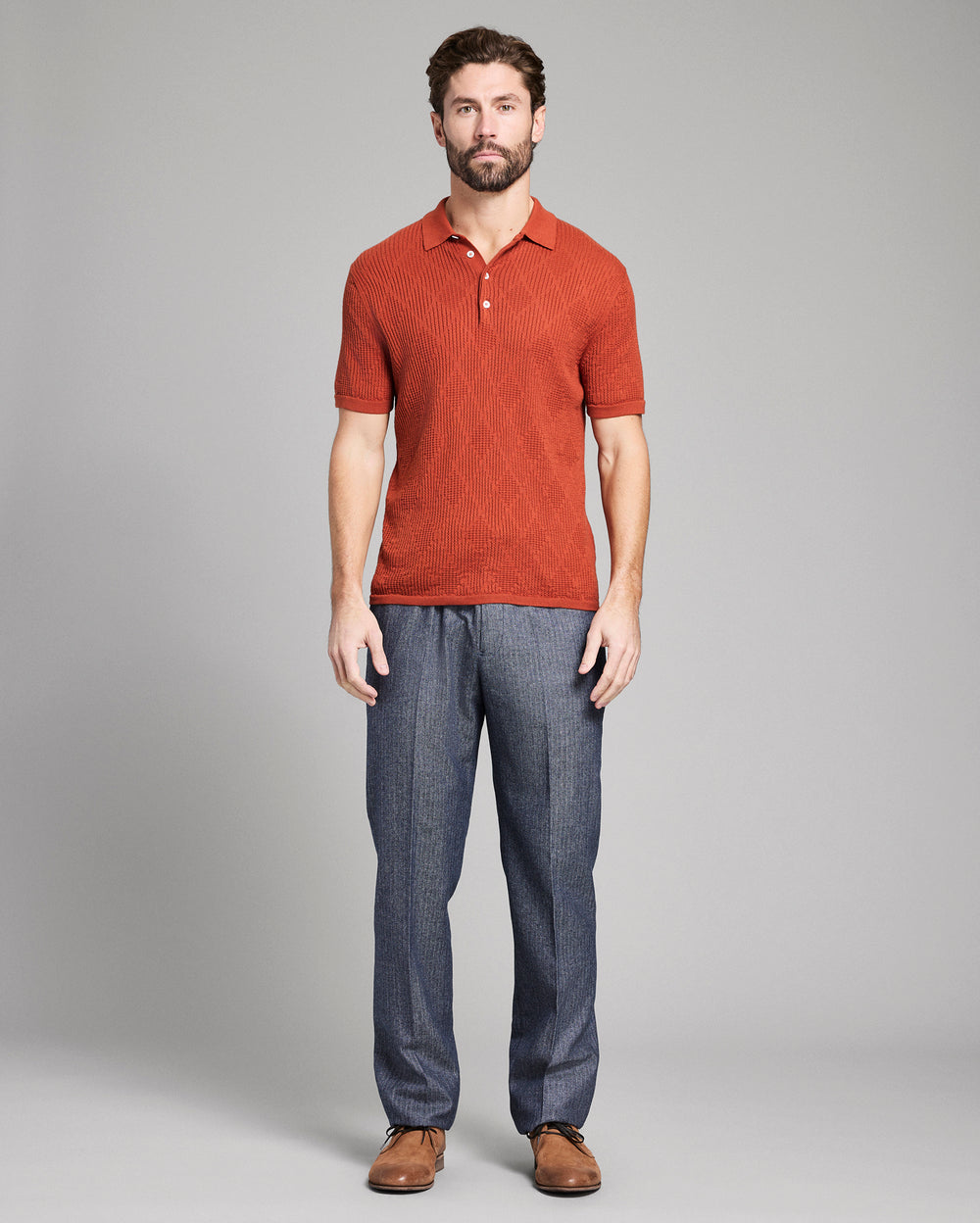 Man wearing a red polo shirt and blue pants on a gray background