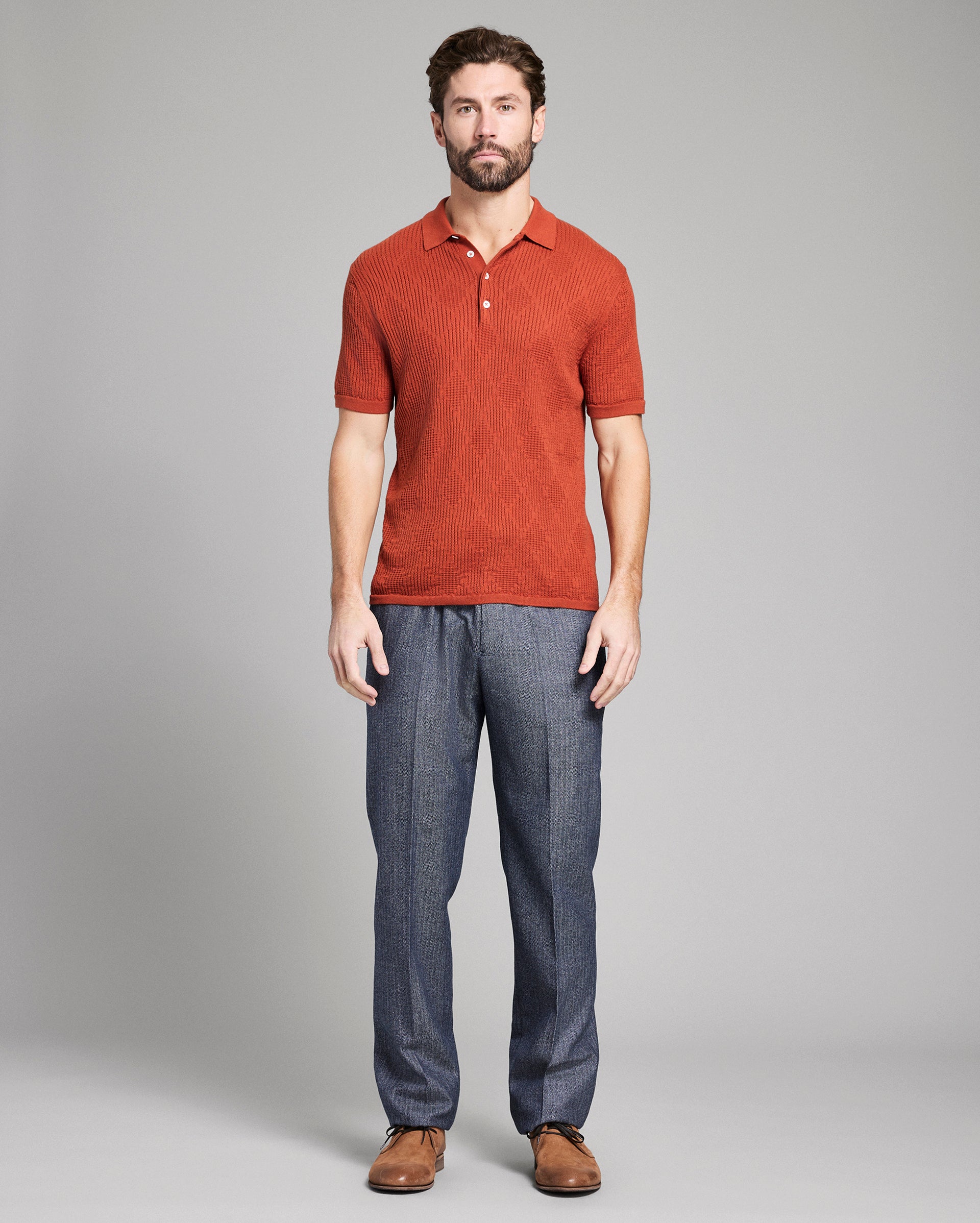 Man wearing a red polo shirt and blue pants on a gray background