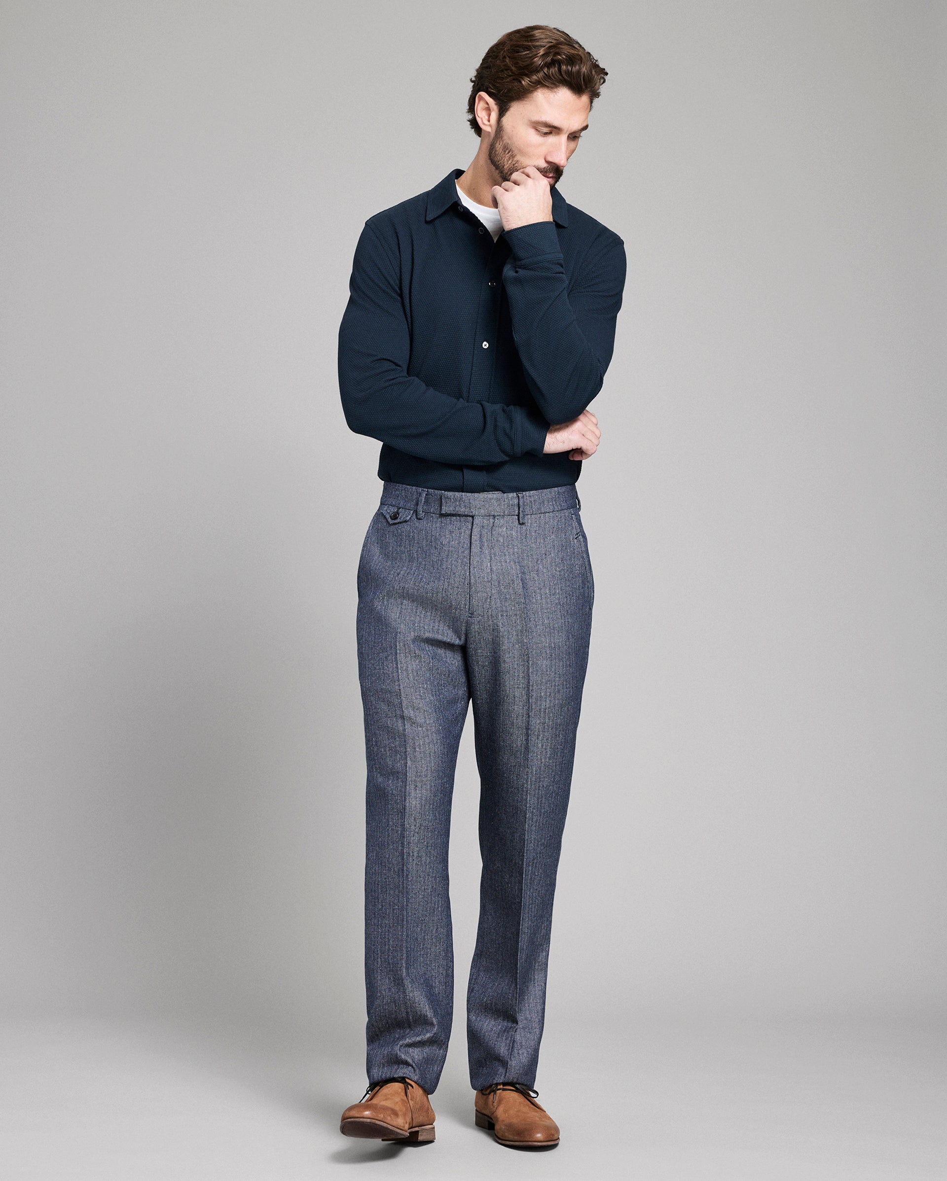 Man wearing a navy sweater and blue plaid pants on a gray background