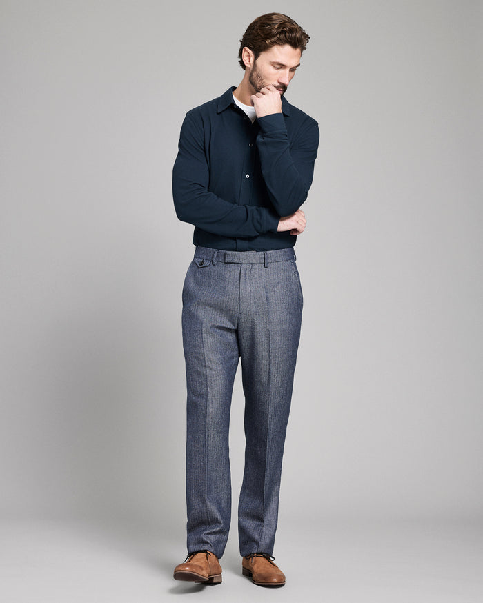 Man wearing a navy sweater and blue plaid pants on a gray background