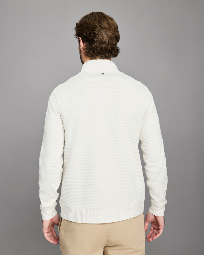 Man wearing a white sweater against a gray background