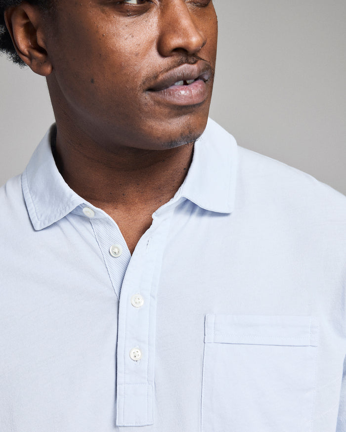 Man wearing a light blue shirt against a gray background