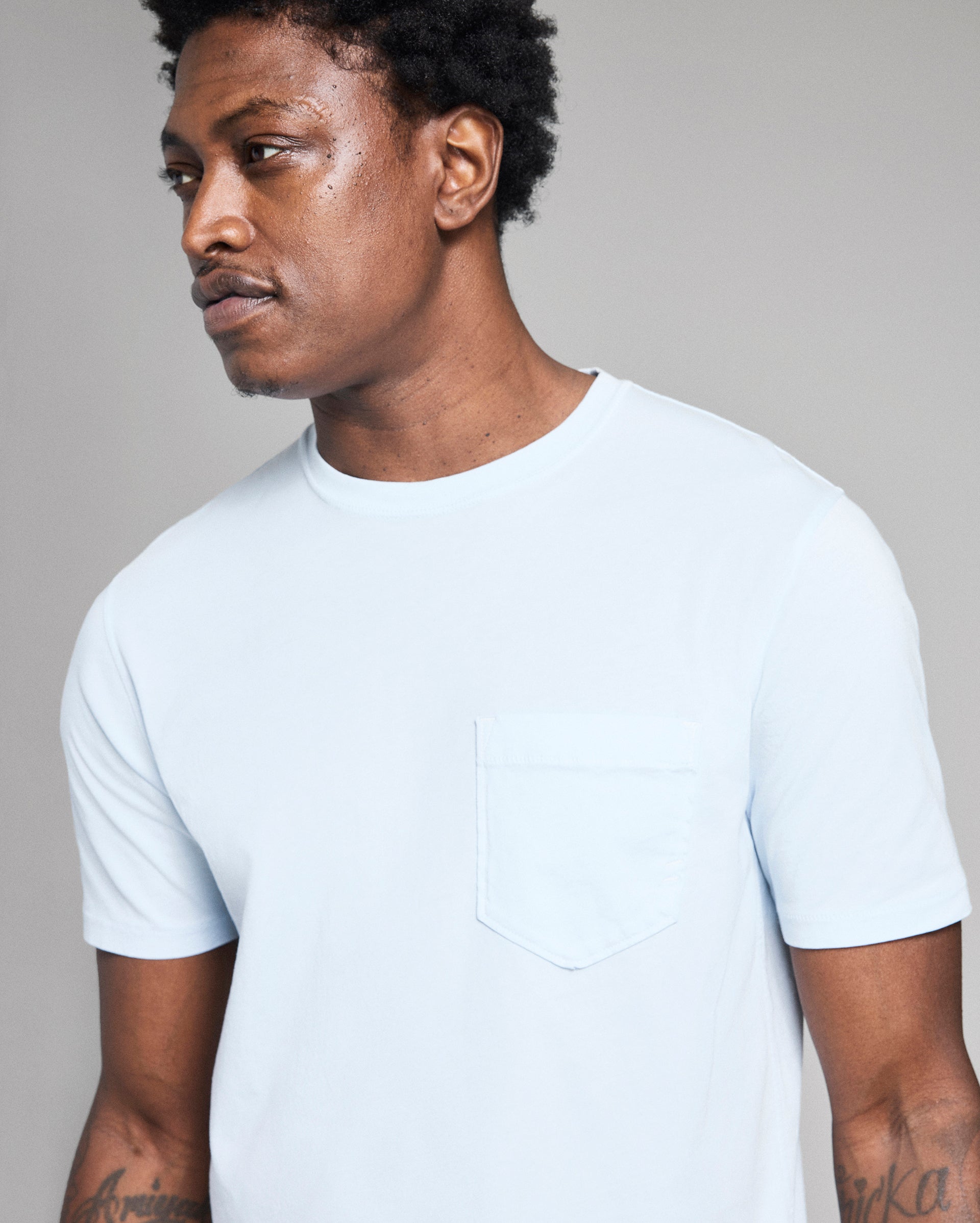 Person wearing a plain white t-shirt against a gray background