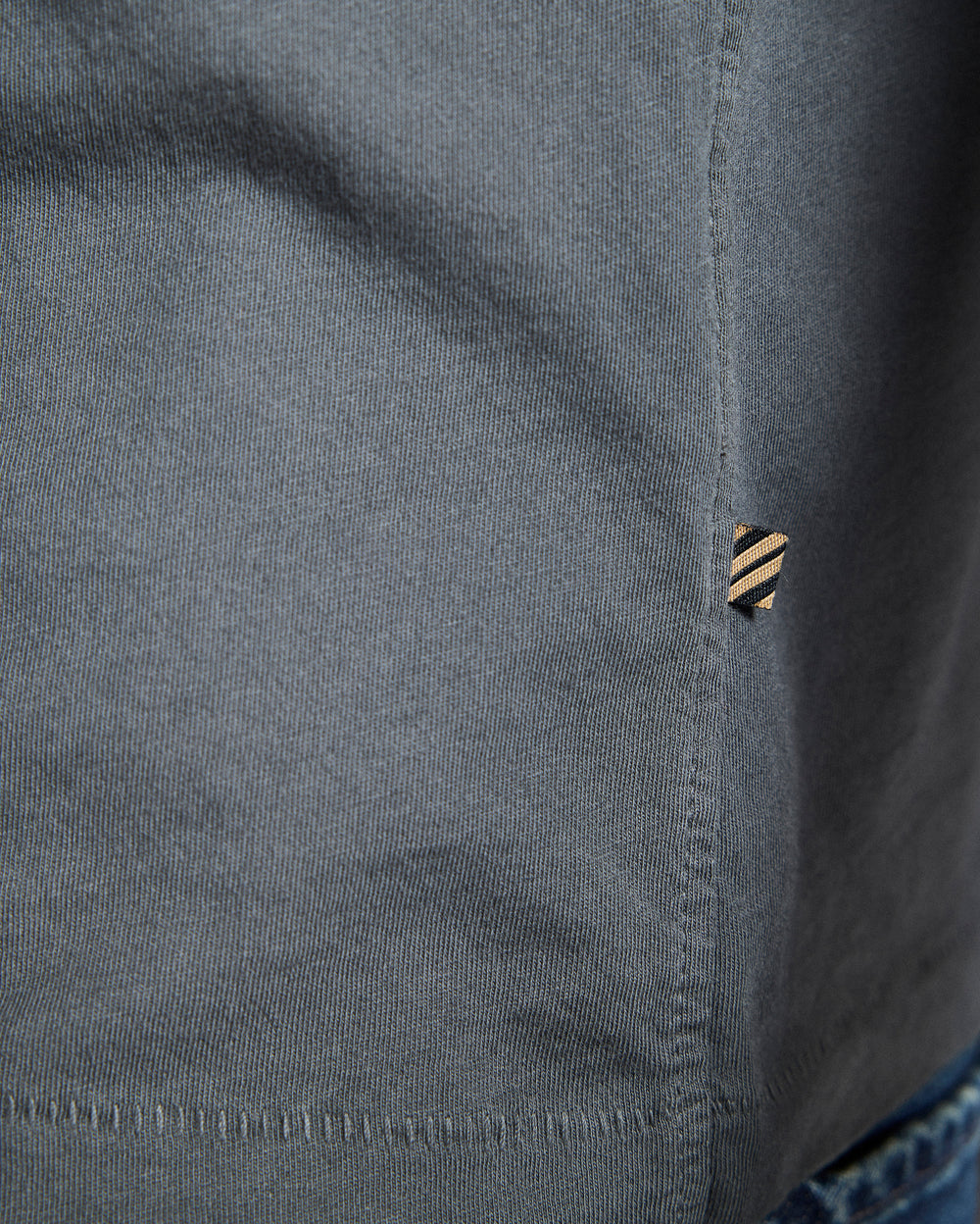 Close-up of a gray shirt with a button and collar detail.
