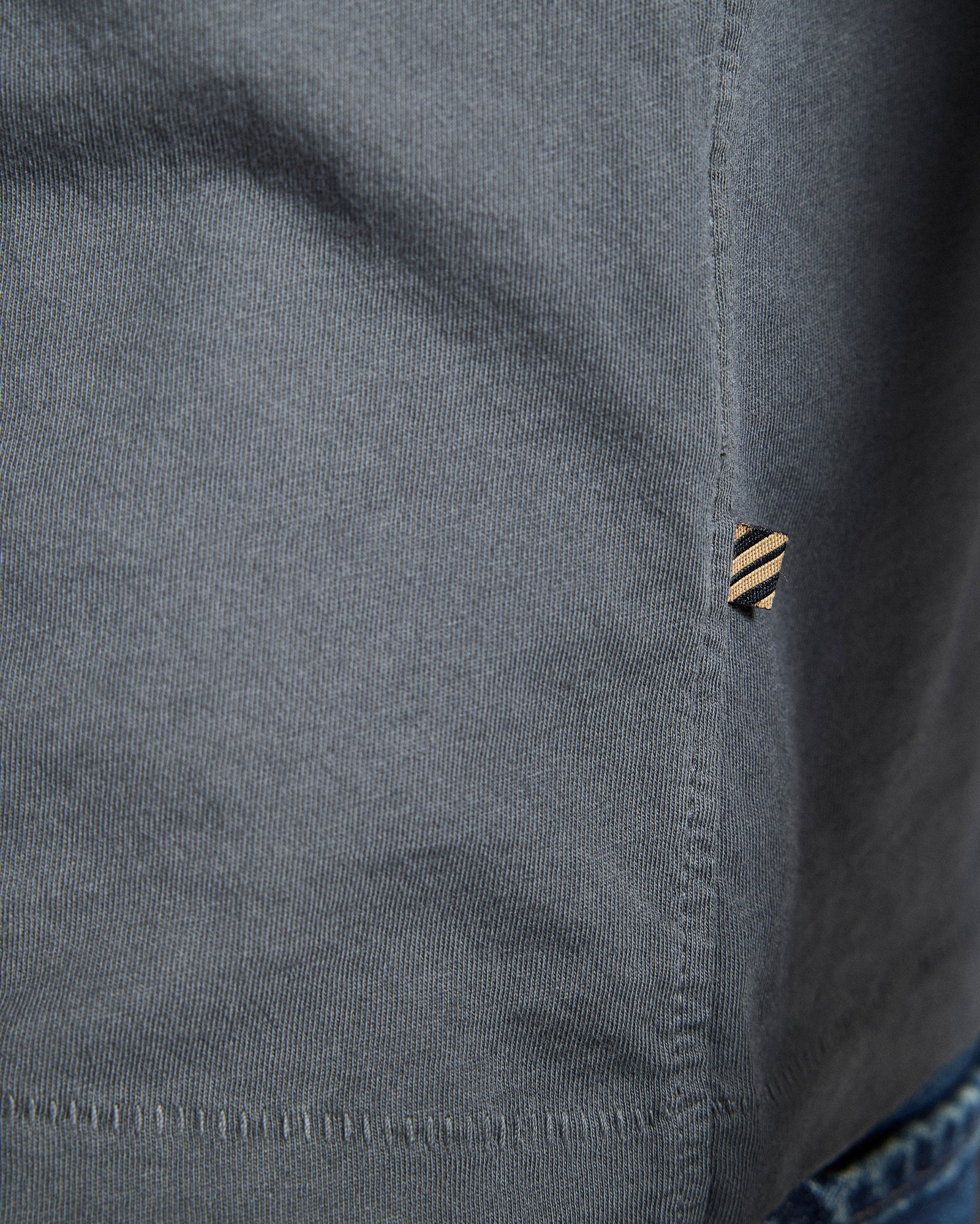 Close-up of a gray shirt with a button and collar detail.