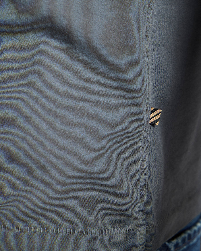 Close-up of a gray shirt with a button and collar detail.