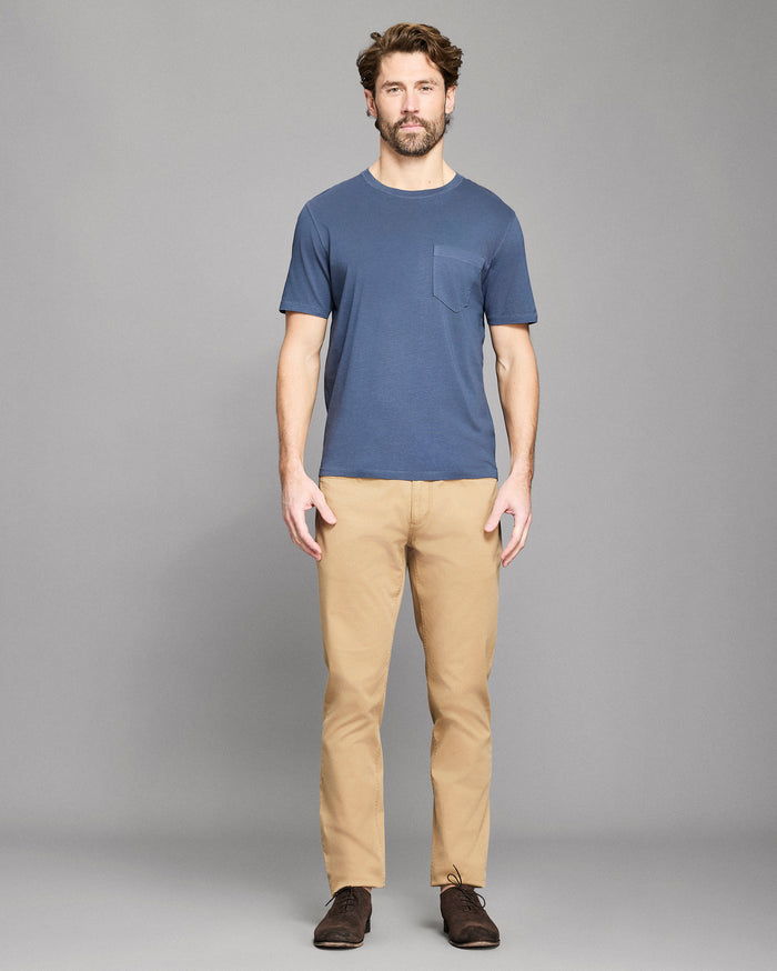 Man wearing a blue t-shirt and beige pants on a gray background