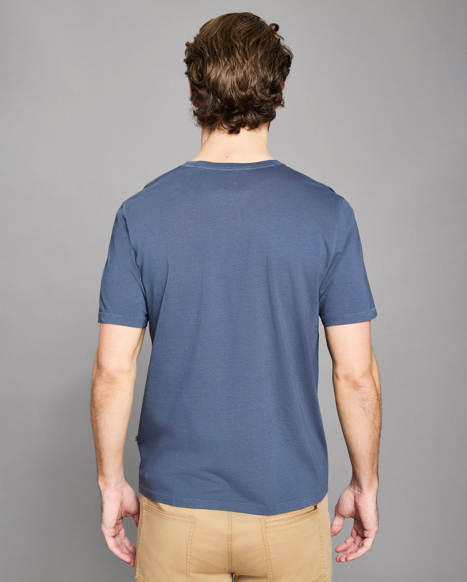Man wearing a blue t-shirt against a gray background