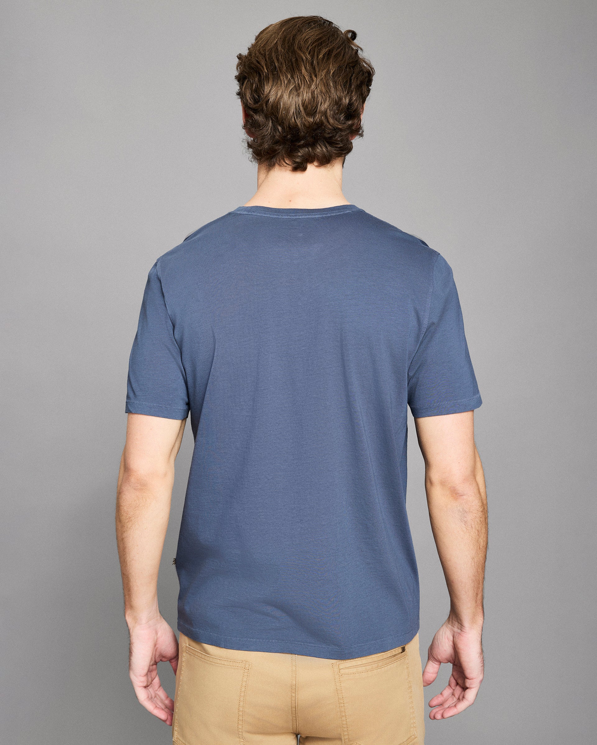 Man wearing a blue t-shirt against a gray background