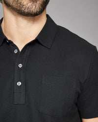 Close-up of a black polo shirt with buttons on a gray background