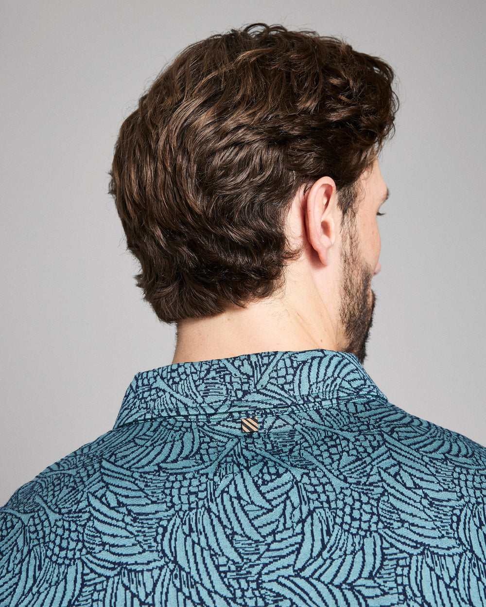 Man wearing a patterned shirt with a neutral background