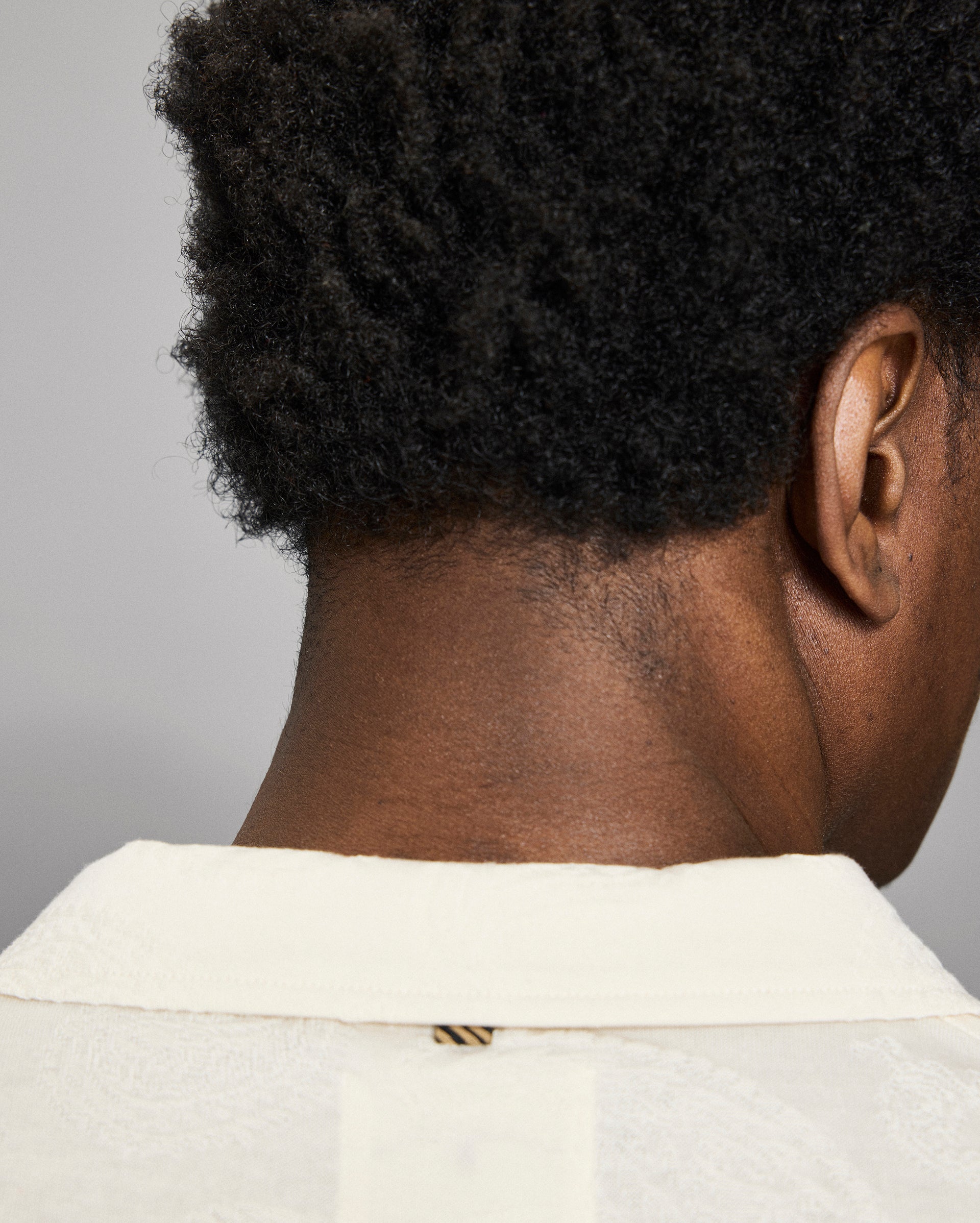 Close-up of a person's neck and shoulder with a neutral background
