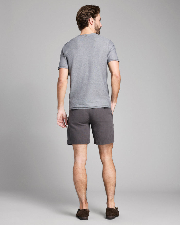 Man wearing a gray t-shirt and shorts on a plain background