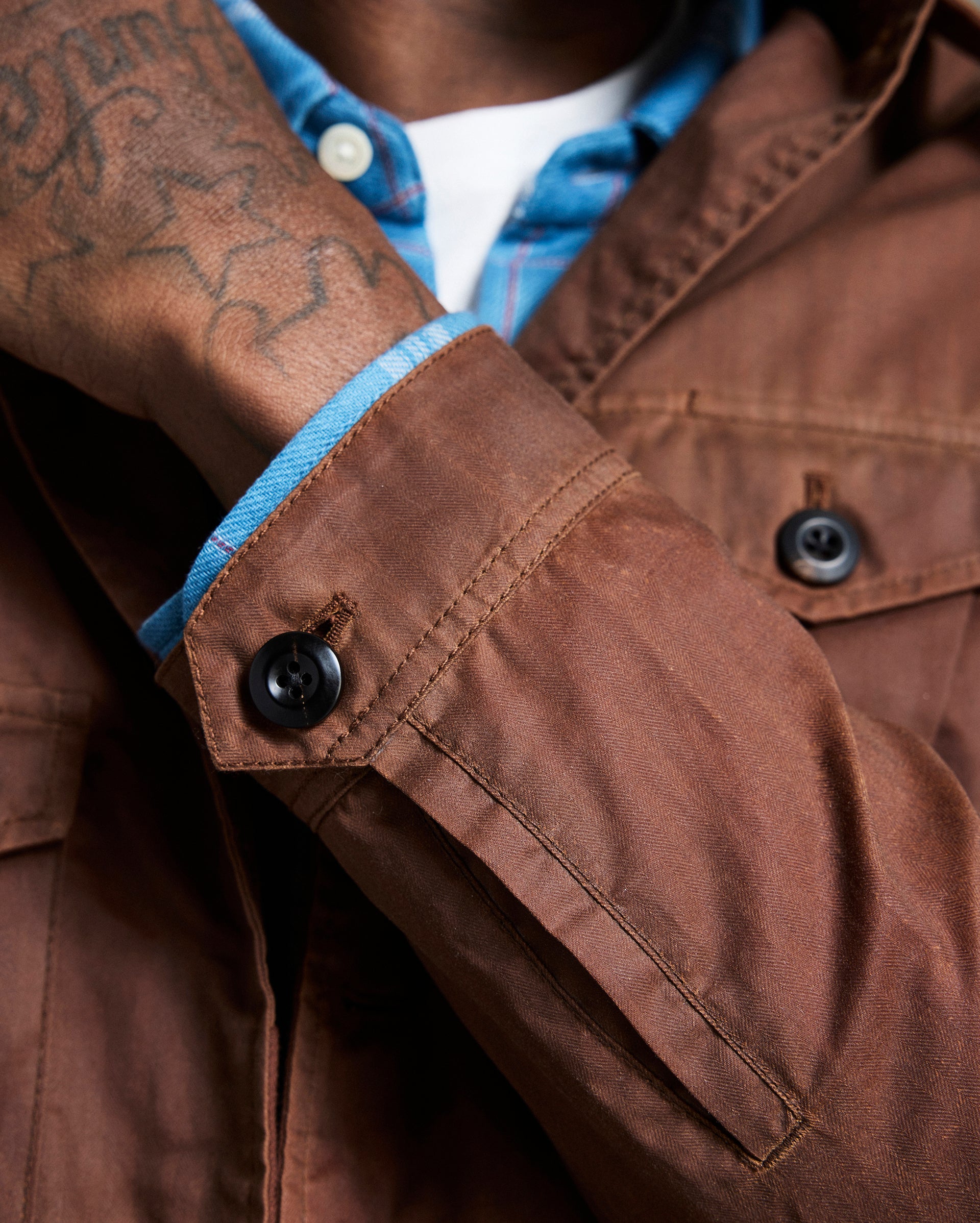 Close-up of a brown jacket with blue lining and visible buttons.