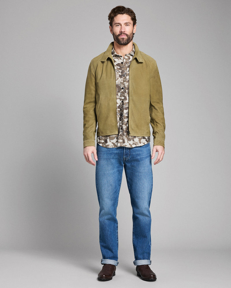 Man wearing a green jacket, camouflage shirt, and blue jeans on a gray background Alternate