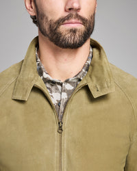 Man wearing a green jacket with a camouflage shirt underneath on a gray background