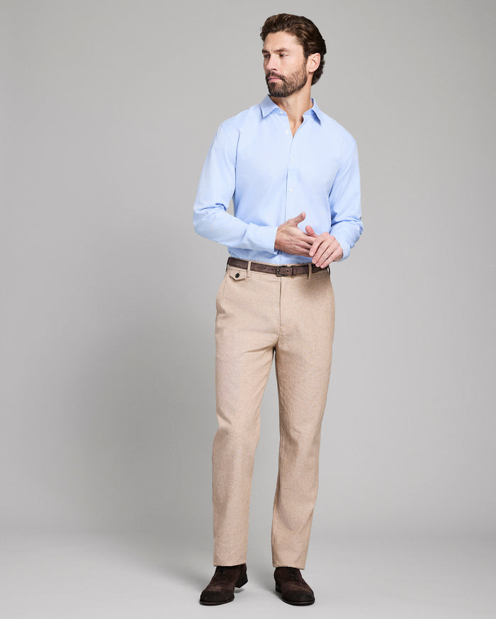 Man wearing a light blue shirt and beige pants on a gray background