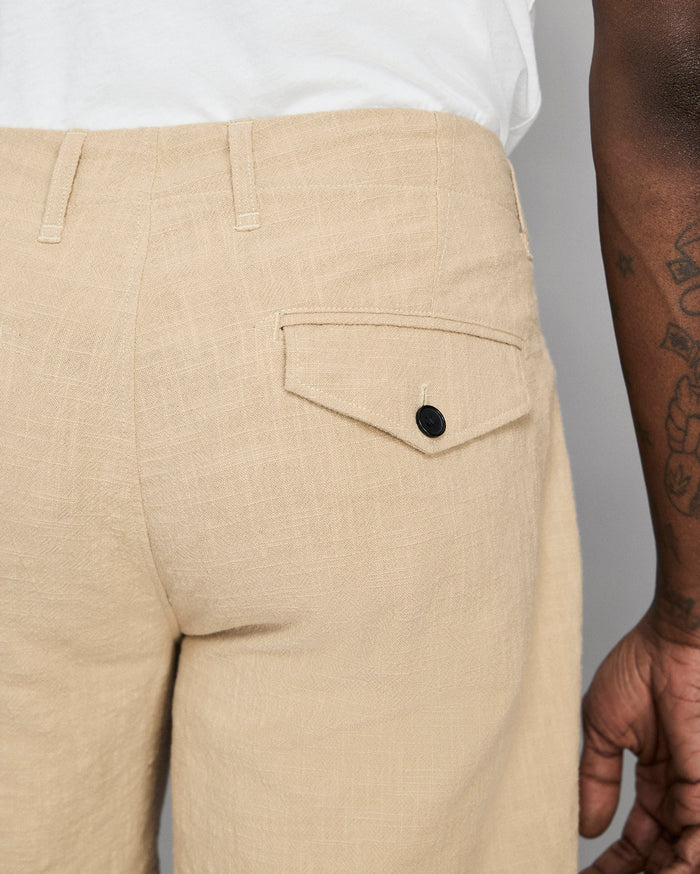 Beige pants with a pocket and button, worn by a person against a neutral background