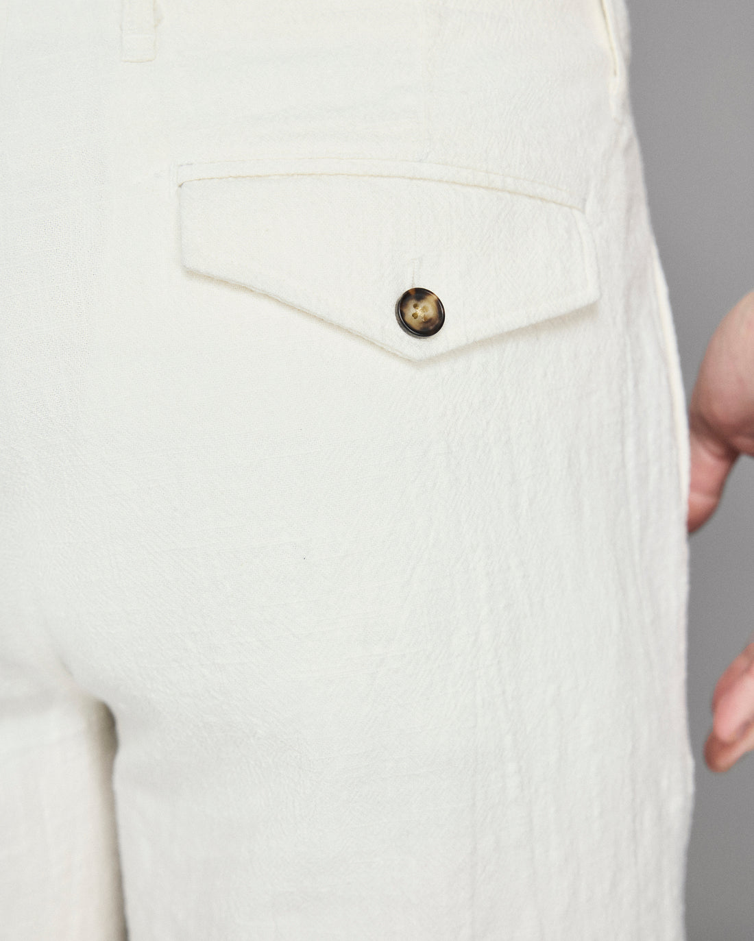 Close-up of a white textured garment with a button on a gray background