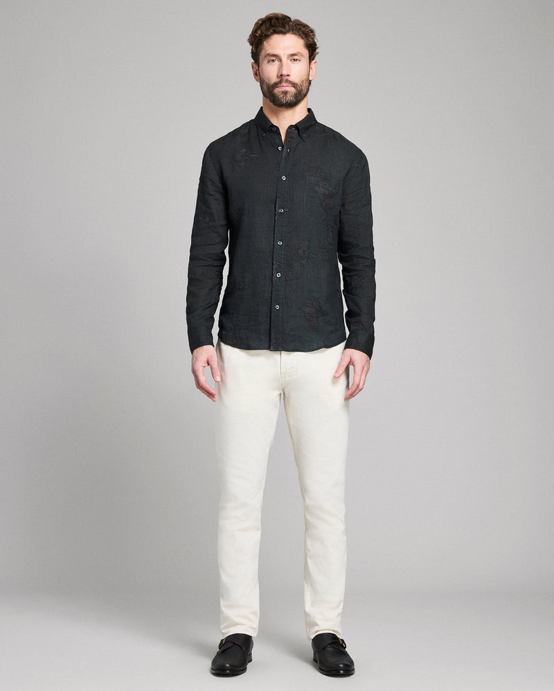 Man wearing a black textured shirt and white pants on a gray background Alternate