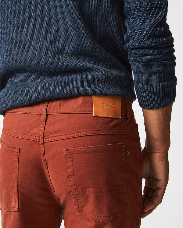 Male model wears the 5 Pocket Pant in Rust Red