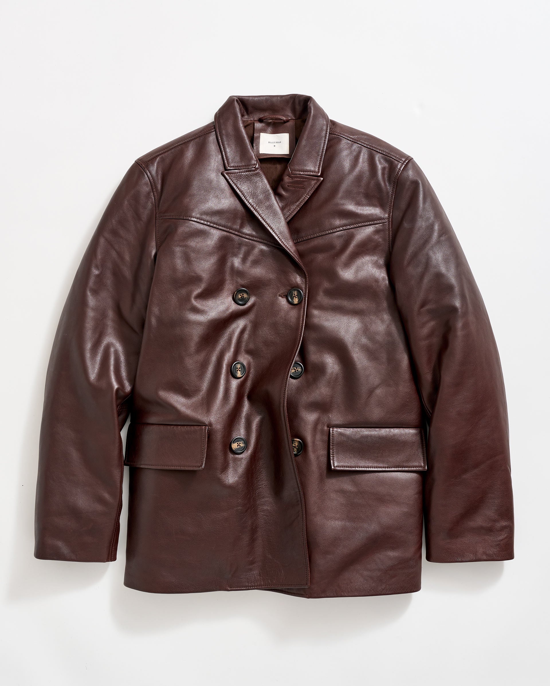 A brown leather double-breasted blazer with four buttons, notched lapels, and two large front flap pockets, displayed against a plain white background.