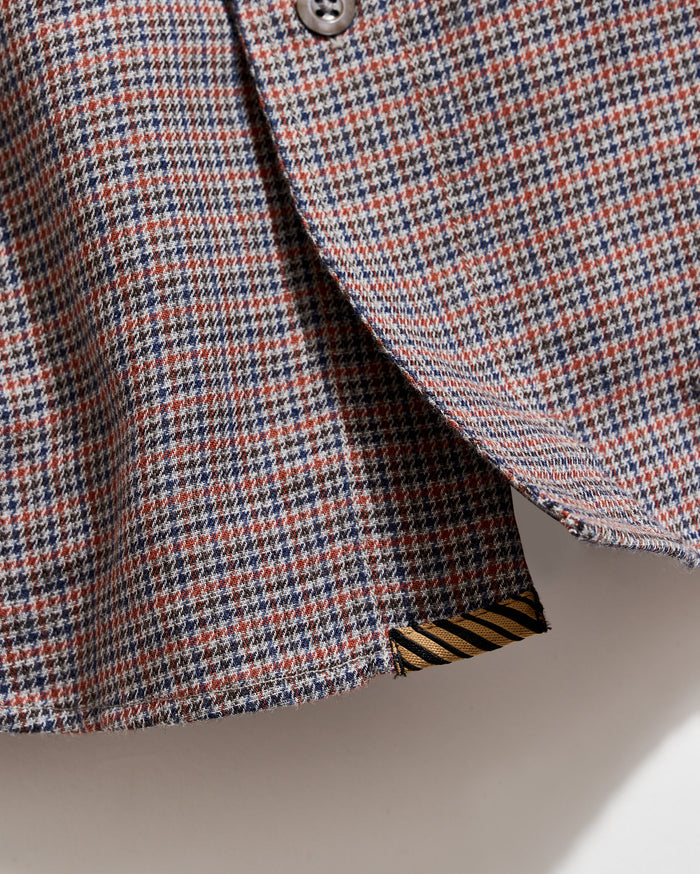 Close-up of a houndstooth patterned fabric with a button on a neutral background