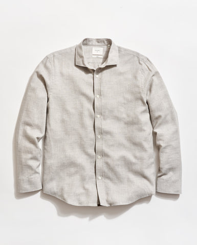A light gray, long-sleeve button-up shirt with a collar, laid flat on a white background. The shirt has white buttons and a slightly textured fabric.
