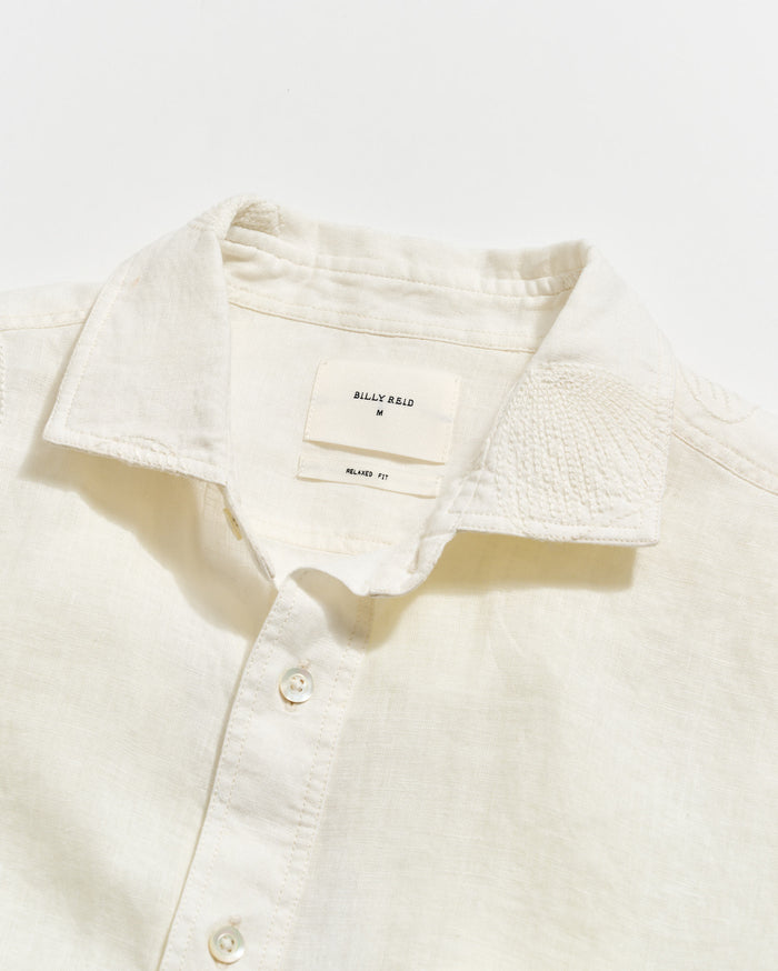 Close-up of a cream-colored shirt with a collar and buttons, featuring the brand 'Bally' on a white background.