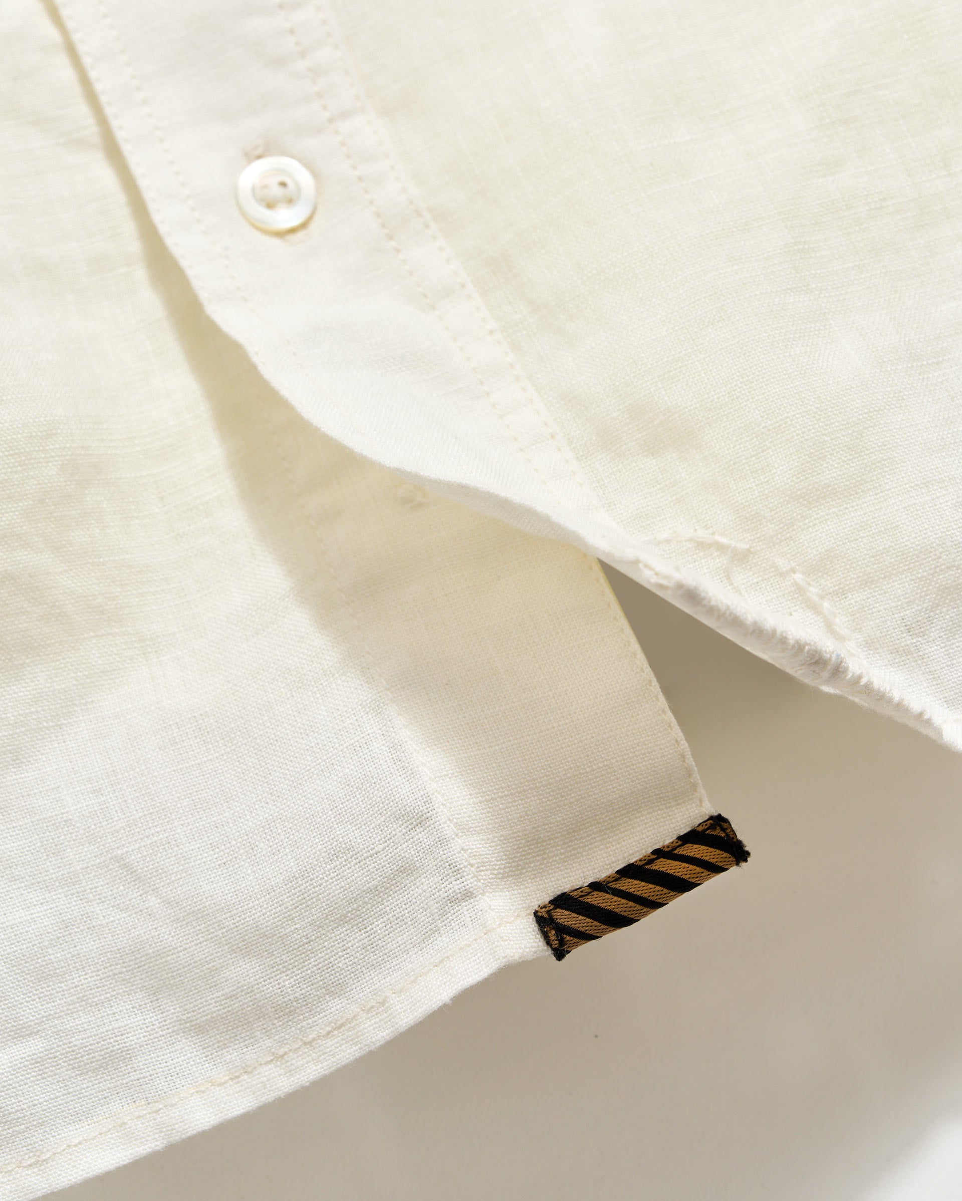 Close-up of a white shirt with a brand label on the collar.