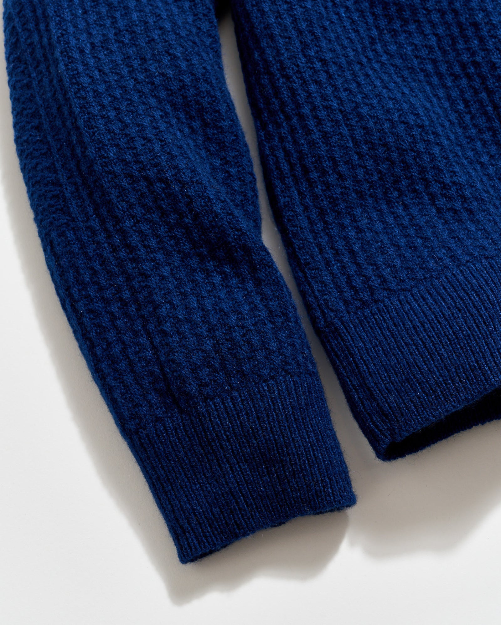 Close-up of a blue textured sweater sleeve on a white background