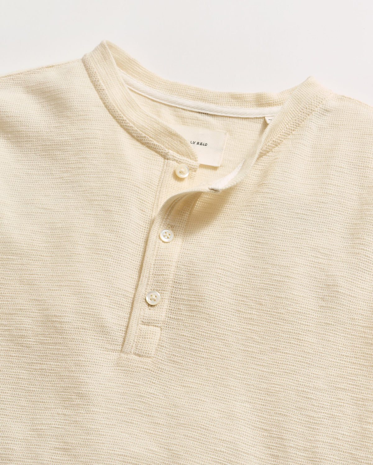 Beige henley shirt with button details on a light background