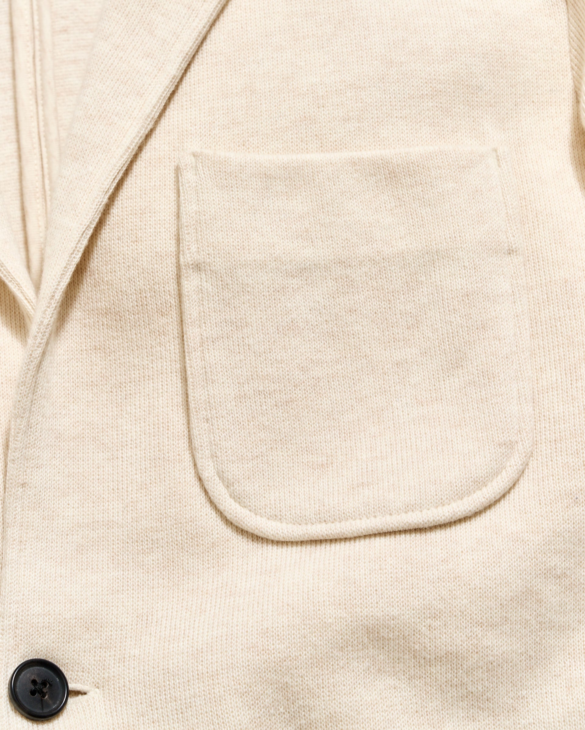 Close-up of a beige jacket with a pocket and button