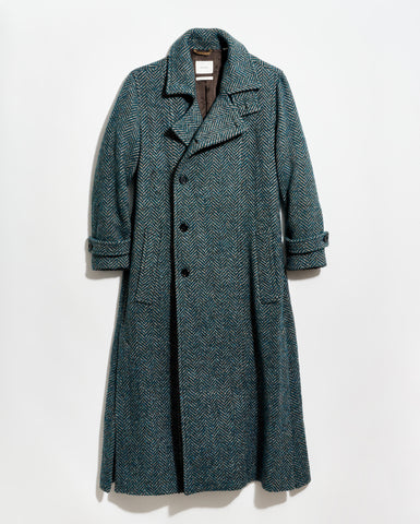 Green herringbone coat on a light gray background