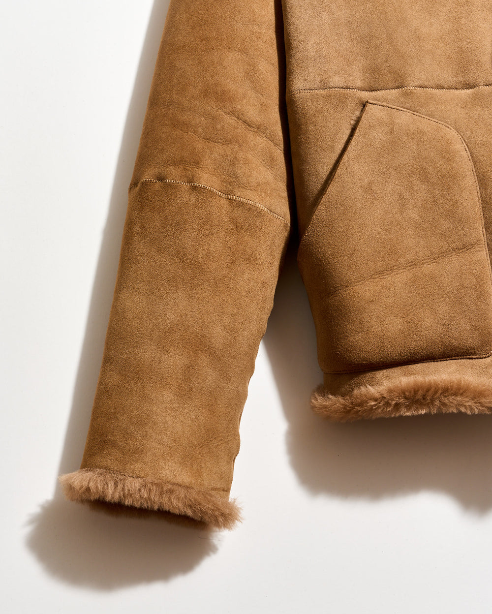 Brown suede jacket with frayed hem on a white background