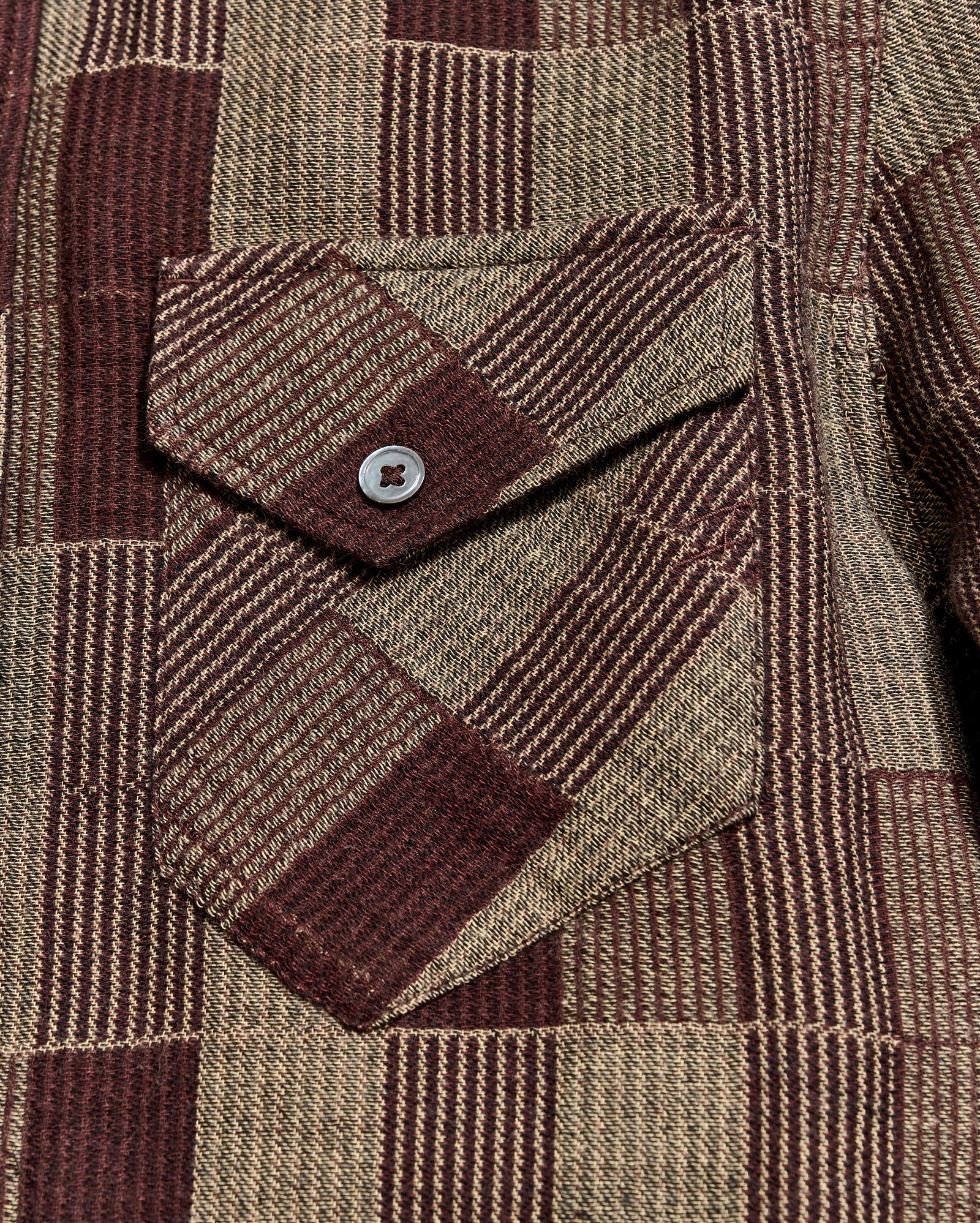 Close-up of a brown and beige plaid fabric with a button pocket detail
