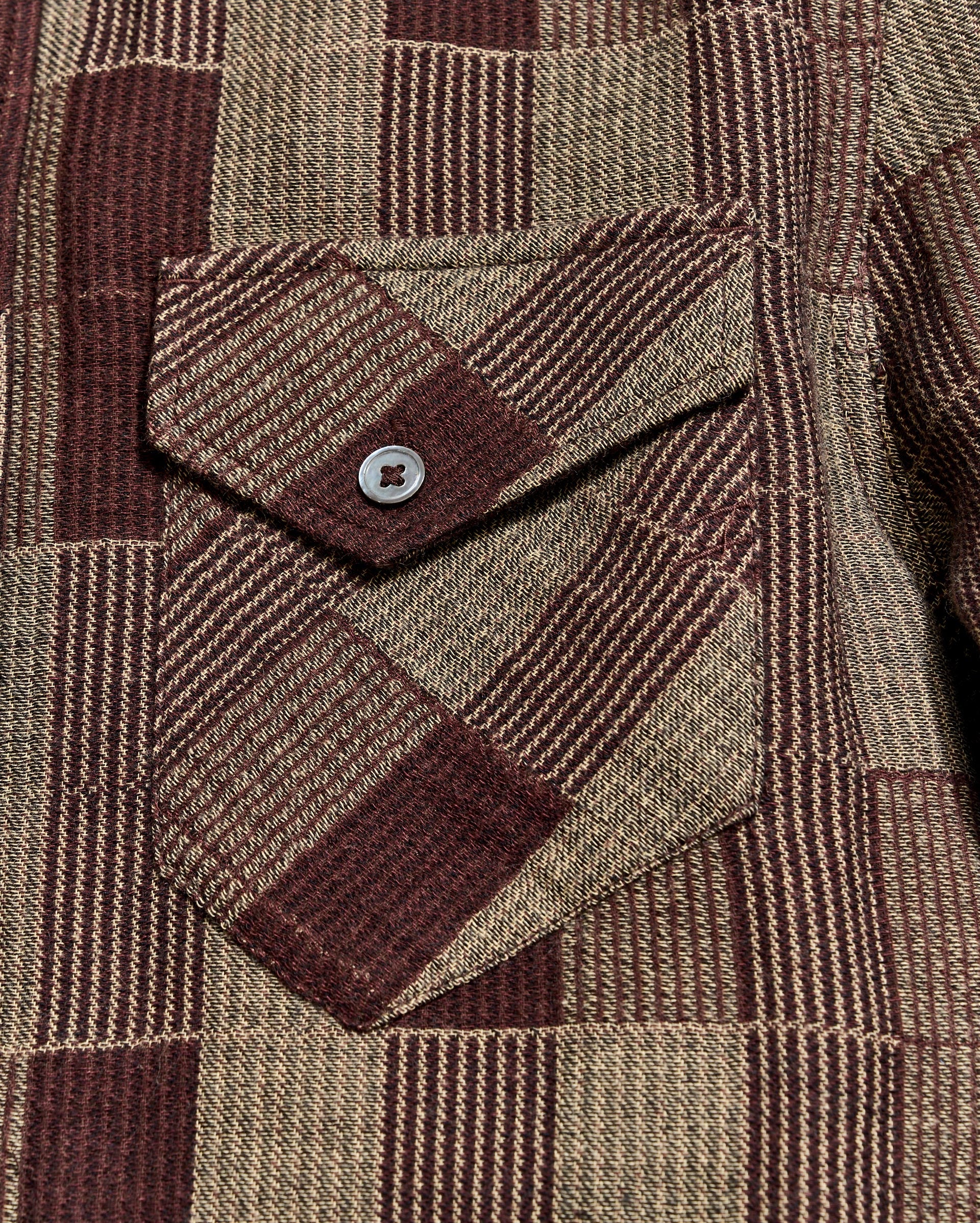 Close-up of a brown and beige plaid fabric with a button pocket detail