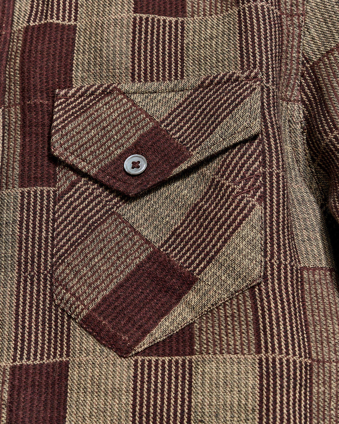 Close-up of a brown and beige plaid fabric with a button pocket detail