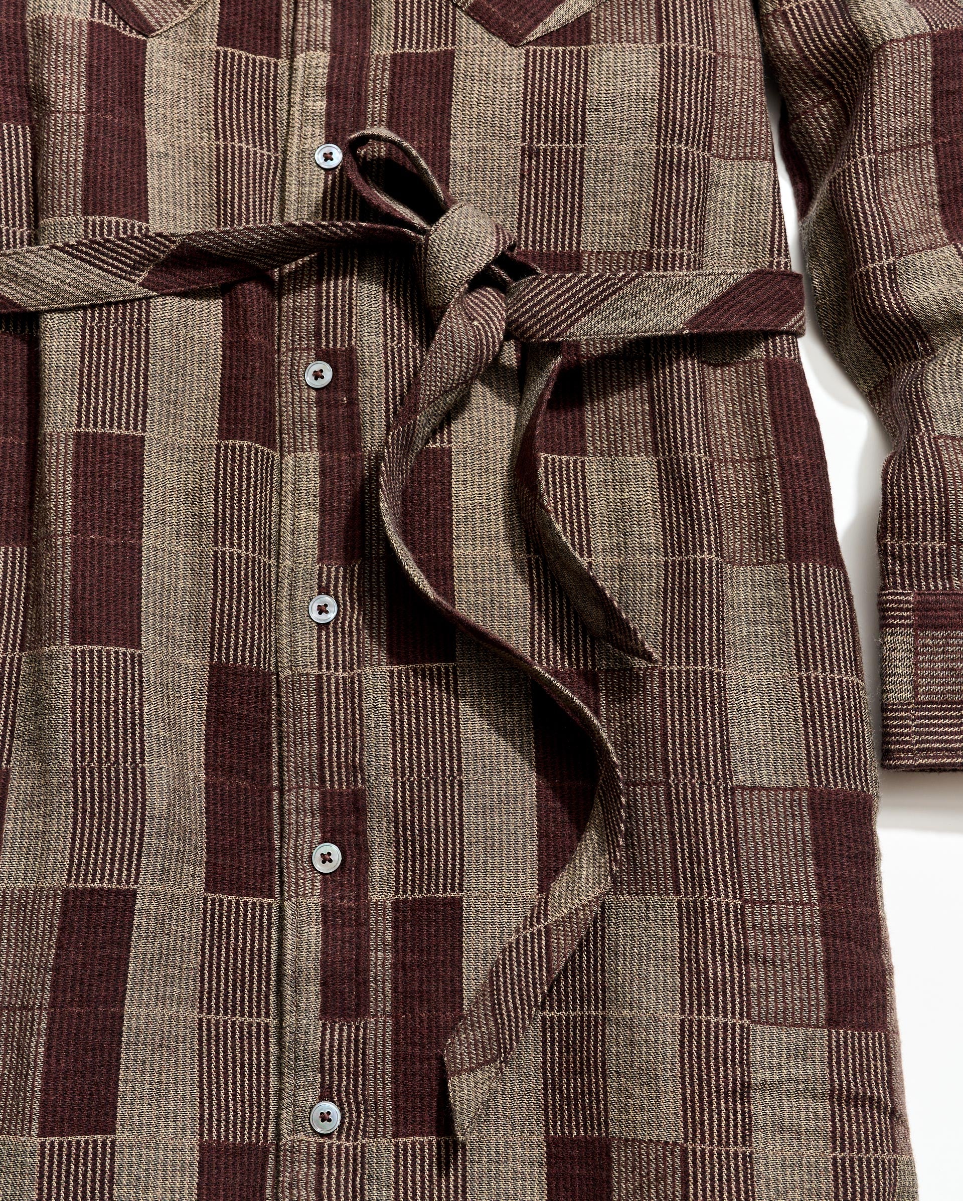 Close-up of a brown and beige checkered dress with buttons on a white background