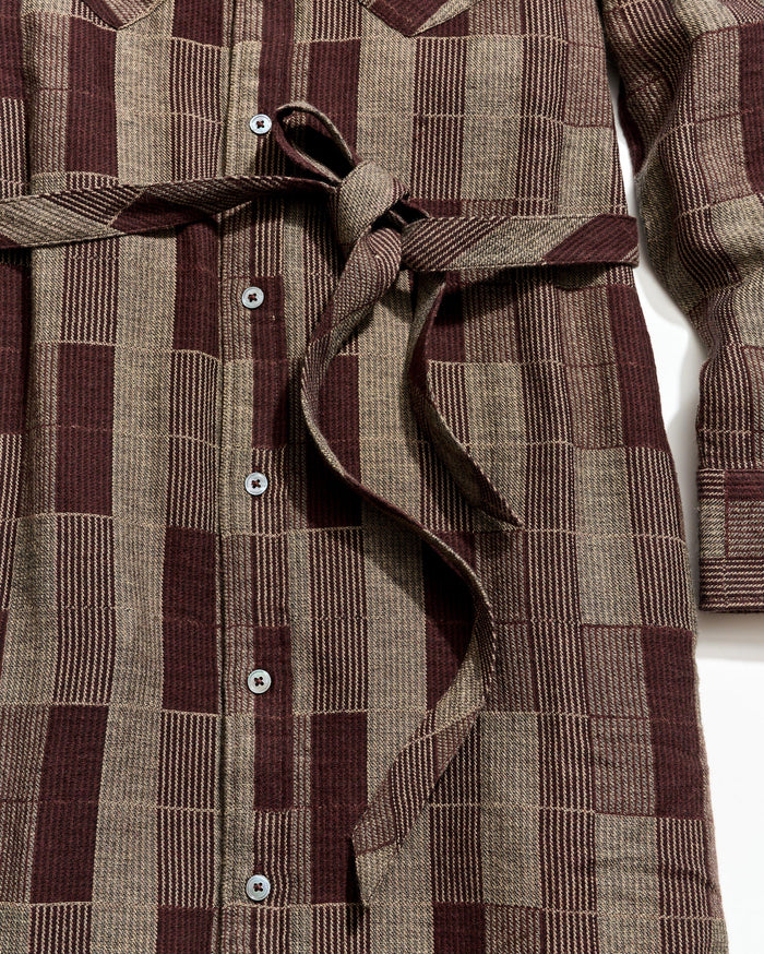 Close-up of a brown and beige checkered dress with buttons on a white background