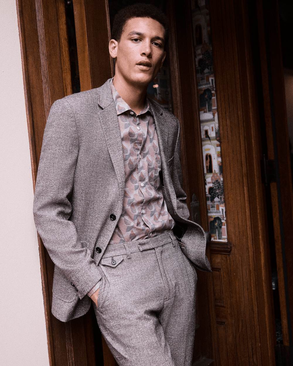 Man wearing a gray suit with a patterned shirt in an indoor setting