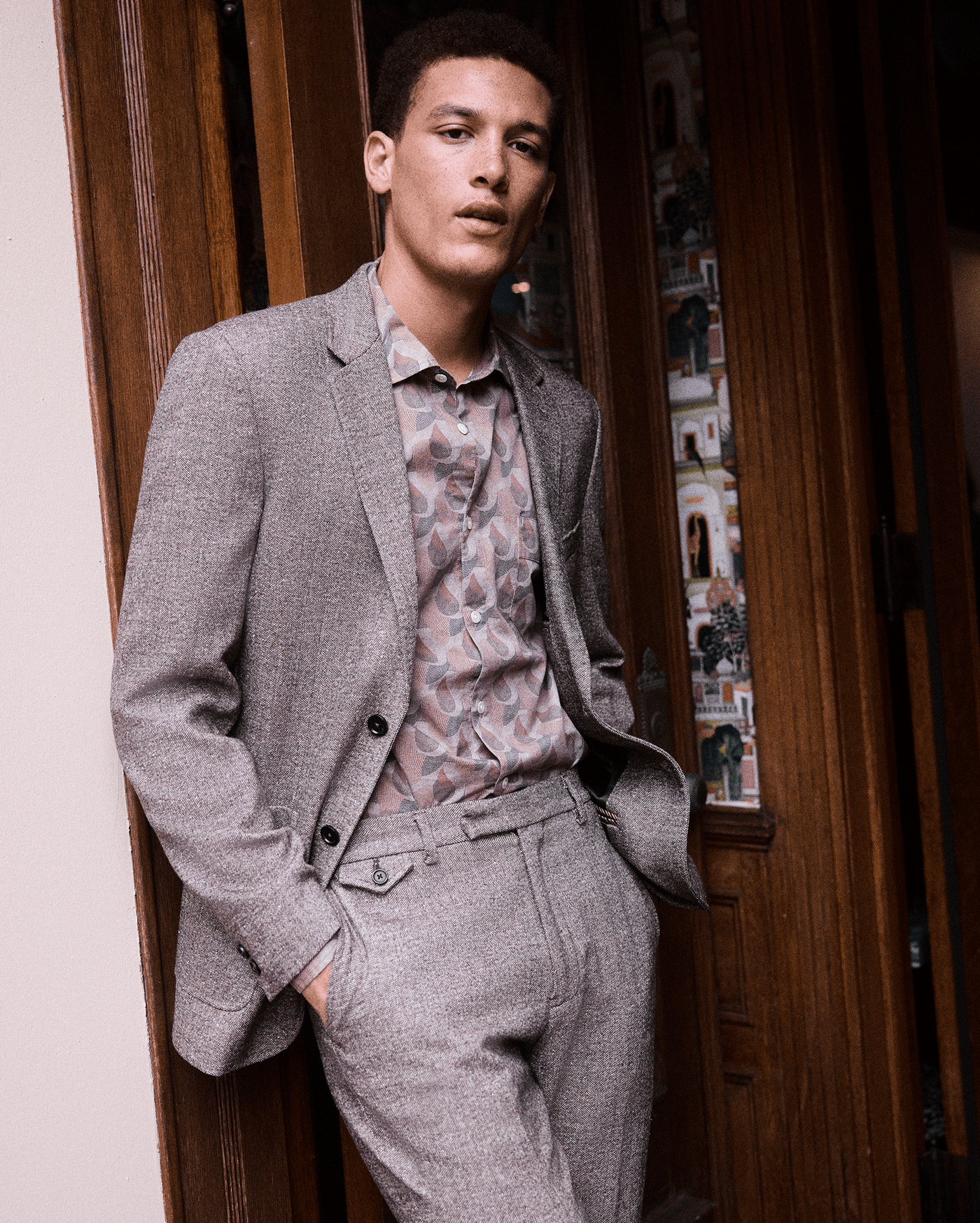 Man wearing a gray suit with a patterned shirt in an indoor setting